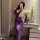Woman wearing purple night temptation sheer lace dress, posing in mirror with flowers and wine glass nearby.
