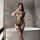 Woman wearing nightsi nightse sexy mesh bodysuit with open-crotch design and thigh-high stockings, posing in bathroom.