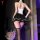 A woman stands with her back to the camera wearing a white top and black skirt with lace trim, paired with stockings and thig...