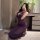 Woman in purple sheer nightsigh nightseduce lingerie set, kneeling by vanity with flowers and champagne glass.