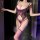 Woman wearing purple sheer lace nightsigh bodysuit with floral cutouts and backless design, posing in dimly lit room.
