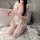A woman wearing a pink maid costume holding a pink whip, posing on a fluffy rug next to a bathtub. the outfit features lace d...