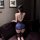 Woman wearing plus size lace halter bodysuit and pencil skirt sleep set, back view on sofa.