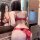 Woman wearing red sheer lace bodysuit with open-crotch design and adjustable ties, viewed from behind in mirror.