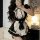 A woman poses with long dark hair, wearing a black and white maid costume featuring ruffles and a bow apron. the outfit inclu...