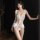 Woman modeling white lace bodysuit with ruffles and open-crotch design, featuring embroidered details and push-up support for...