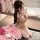 Woman in beige lace bondage outfit with sheer sleeves, posing with pink roses for date night role play.