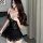 Woman wearing black lace sleepwear dress with sheer panels and ruffled hem, styled for seductive bedtime lounge wear.
