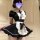 A woman wearing a black and white maid costume set, featuring a ruffled apron and short sleeves, posing indoors.