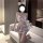 Woman in pure & playful jk sleepwear set with plaid skirt, bow top, and mouse ears, holding plush toy.