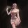 Woman wearing pure & playful lace lingerie set with pearl accents and red bows, holding a wand in dim lighting.
