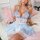 Woman wearing blue and white pure & playful lingerie sleep dress with waist cinching, princess style mini nightgown on bed.