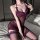 Woman modeling a sheer purple lace lingerie set with matching stockings on a bed.