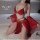Woman wearing red pure & seductive lingerie set with sheer sleeves and gold accents, kneeling on bed for couples’ roleplay or...
