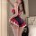 Woman wearing red and navy blue lace bodysuit with ruffles, open-crotch design, and white thigh-high stockings in bedroom set...