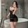Woman in bathroom wearing black lace sleep set with sheer mesh and uniform style design, holding phone for mirror selfie.