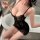 Woman in black lace sleep set with sheer mesh, posing seductively by bathtub — sexy uniform-style nightwear for intimate mome...