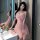 A woman poses elegantly beside a sink wearing a delicate pink lace cami sleepwear dress, featuring a matching bralette and br...