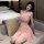 A woman lounges on a couch wearing a delicate pink lace cami sleepwear dress, featuring a matching bralette and briefs set, e...
