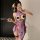 Woman in purple qqny silk-look cheongsam lingerie set with pearl chain, floral hairpiece, fishnets, holding fan and phone.