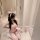 Woman in pink rabbit girl lingerie set with bunny ears, holding plush toy, kneeling on marble floor.