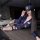 Woman in blue rabbit police officer lingerie set with cap, sheer stockings, and harness, posing seductively on table.