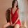 A woman sits elegantly on an antique chair wearing a red lace sheer backless slip dress, perfect for new year celebrations an...