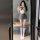 A woman poses in a mirror wearing a cute japanese school uniform style jumpsuit with a bow tie, knee-high socks, and white st...