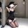 Woman kneeling in black lace lingerie set with sheer mesh bodysuit, garter stockings, and long gloves.