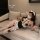 Woman lounging on a sofa in a seductive maid-style lingerie set, featuring a black and white dress with frills, thigh-high st...