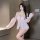 Woman wearing pink sheer lace princess sleep set with open bust, bare-butt design, and flowing sleeves in modern room.