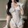 Woman wearing white sheer bunny lingerie set with ruffles, cut-out top, and open-crotch design for adults.