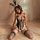 Woman wearing a sexy bunny girl bodysuit with cut-outs, sheer mesh, and fishnet stockings, posing on a bed.