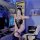 Woman in sexy bunny girl lingerie set with open-crotch bodysuit, posing in gaming room setup.