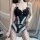 Woman wearing black lace bodysuit with ties, sheer panels, and fishnet stockings in a seductive open-crotch design.