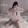 Woman in sexy lace sheer sleepwear set with open-crotch bodysuit, posing on bed for intimate wear.