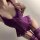 Woman wearing purple lace lingerie set with sheer mesh details and garter straps, designed for a busty look.