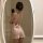 Woman wearing a sheer backless lace slip dress, capturing a mirror selfie in a seductive thin mesh lounge set.