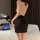 Woman wearing black sheer lingerie skirt and bodysuit set, back view on bed with laptop. plus size sexy sleepwear ensemble.