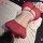 Woman wearing red sheer cheongsam lingerie with lace trim and adjustable ties, lying on textured blanket with rose petals.