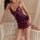 Woman wearing purple lace sleepwear set with bow details, posing on tufted sofa in romantic bedroom setting.