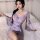Woman wearing sheer lavender butterfly print kimono robe with peek-a-boo braless design, seated on bed holding lace fan.