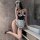 Woman modeling suqing sexy maid costume set with lace trim, halter neck apron, and black heels in a modern bathroom.