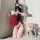 Woman in red suqing vintage lace bodysuit with embroidered bindings, posing by door with pink roses.
