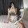 A stylish young woman poses on a bed wearing a charming plaid maid dress with lace trim, perfect for cosplay or youthful allu...
