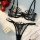 Black sheer lace lingerie set with red roses and pearls on white fabric.
