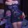 Woman wearing a sexy, one-shoulder lace bodycon skirt set, holding a red rose in a romantic bedroom setting.