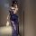 Woman wearing a navy blue lace slip dress with side slit, holding a feather accessory in a mirror selfie.