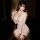 Woman wearing pink floral deep v bodysuit with bow-tie and thong cutout, sensual sleepwear set in dim lighting.