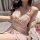 Woman wearing a pink lace cami set with bow details, sitting beside pink roses.